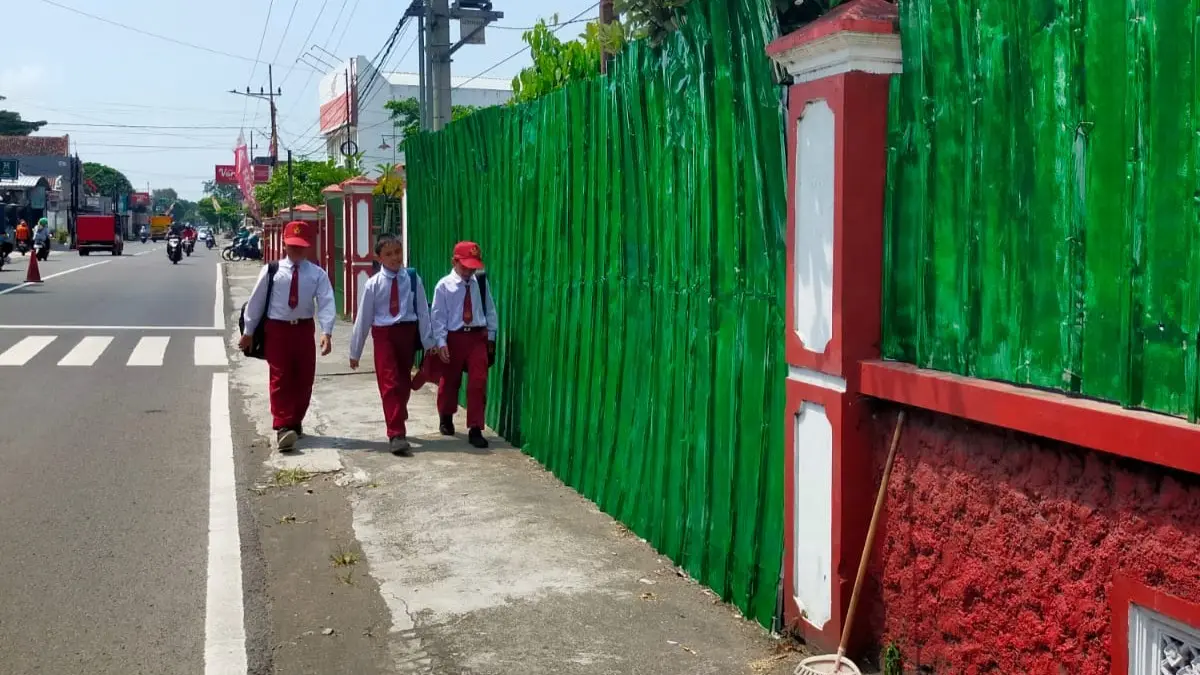 tiga siswa menyusuri tembok seng pembangunan KDMP di lingkungan sekolah